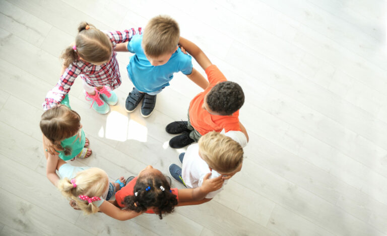 Little children making circle with hands around each other indoo